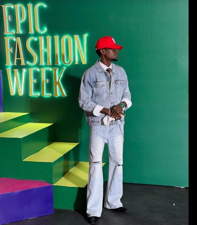 Denim two-piece and red cap against the green Epic Fashion Week backdrop