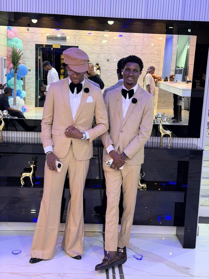 Two men in matching tan suits with bow ties at a wedding